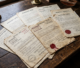 Old property deeds and legal documents with seals on wooden table