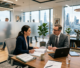 Two business professionals discussing paperwork at a desk with laptop and notepad
